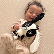 Load image into Gallery viewer, Smiling baby cuddling Billie the Bunny high contrast black and white sensory toy – ideal for newborn bonding and visual development