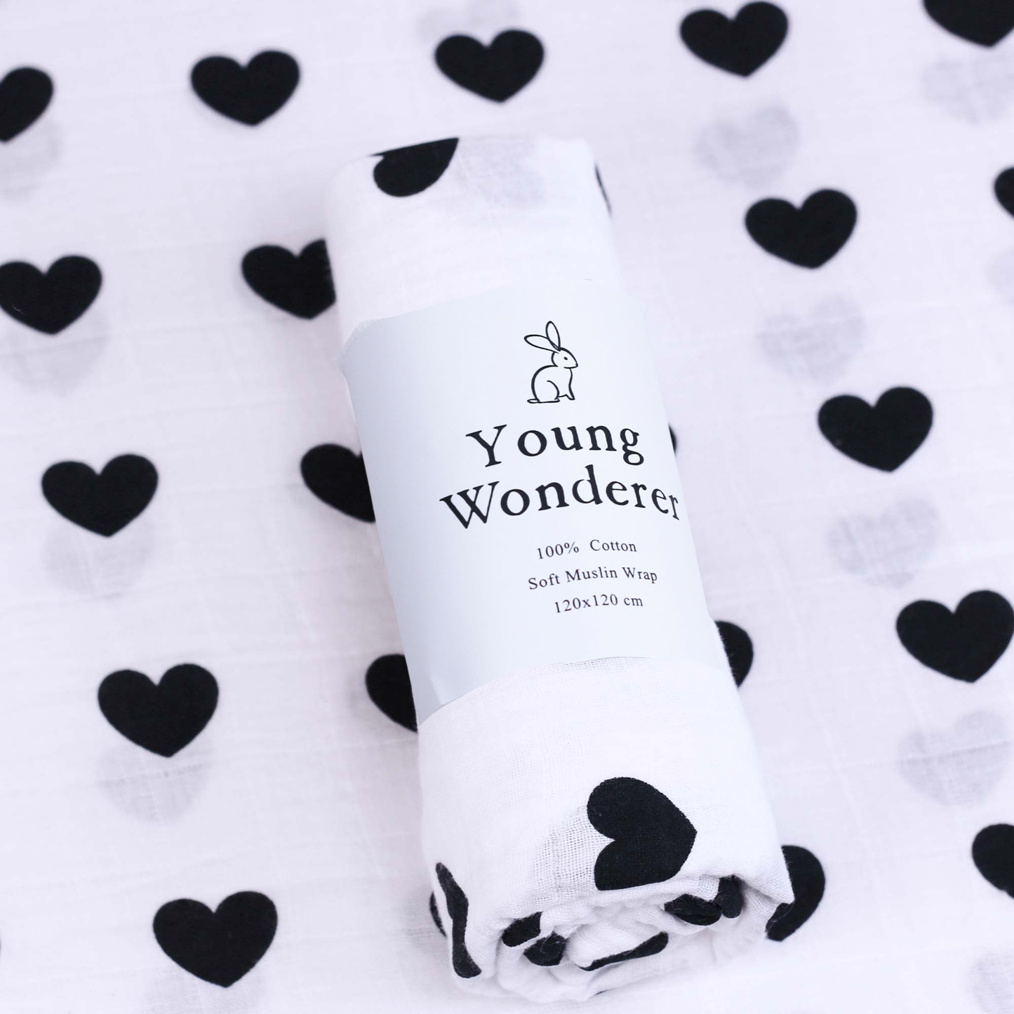White muslin wrap with 'Young Wonderer' branding on a white background with black heart patterns.